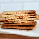 A stack of sourdough graham crackers on a piece of parchment paper.