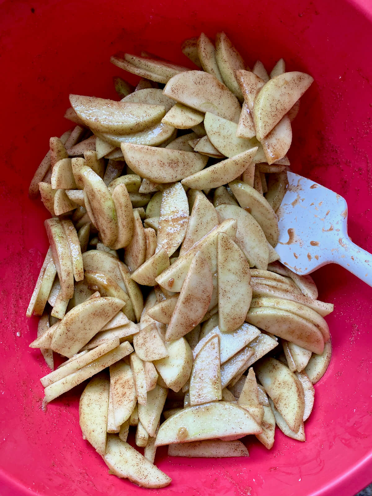 Sliced apples mixed with brown sugar, warm spices, and other ingredients to make the apple pie filling.