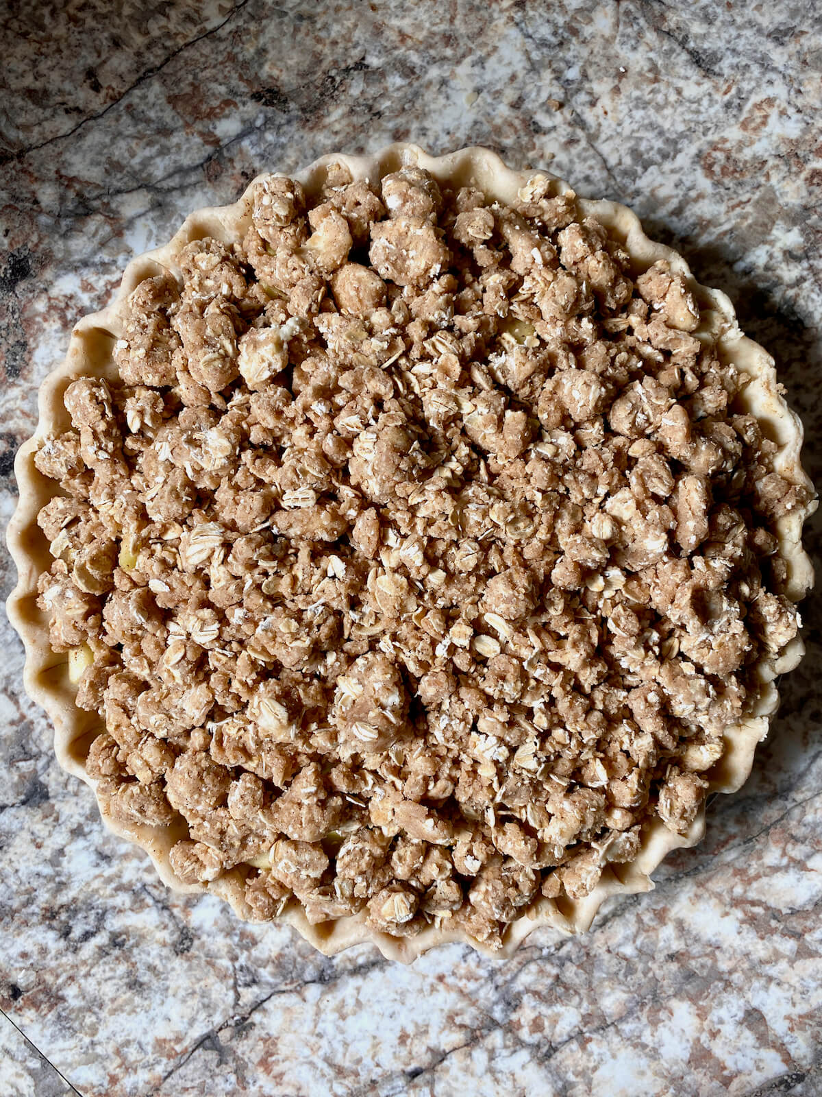 The assembled apple pie with sourdough oat crumble on top.