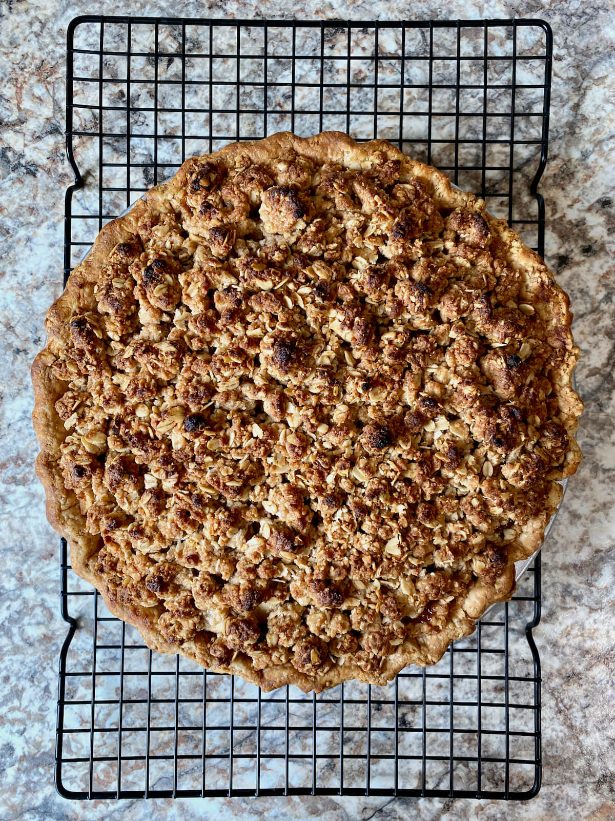 The baked sourdough apple pie cooling on a wire rack.