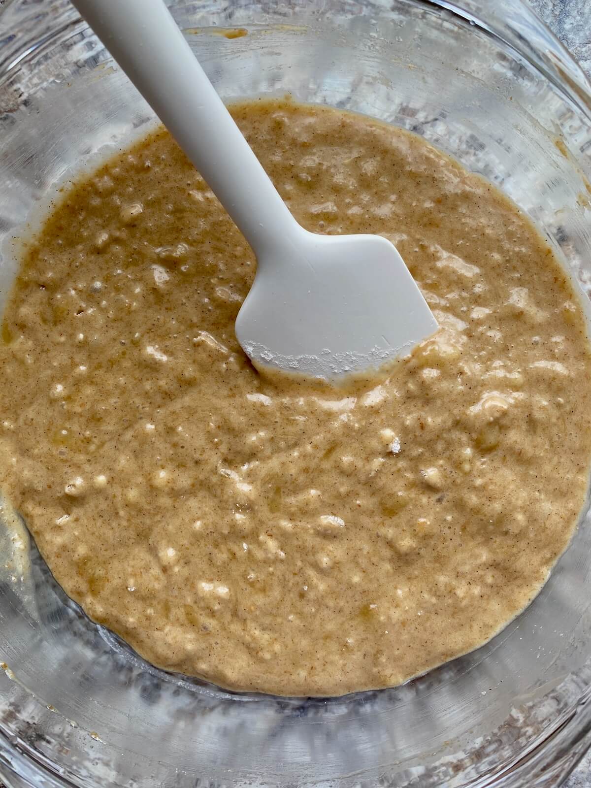 Sourdough discard banana muffin batter in a bowl with a rubber spatula sticking out.