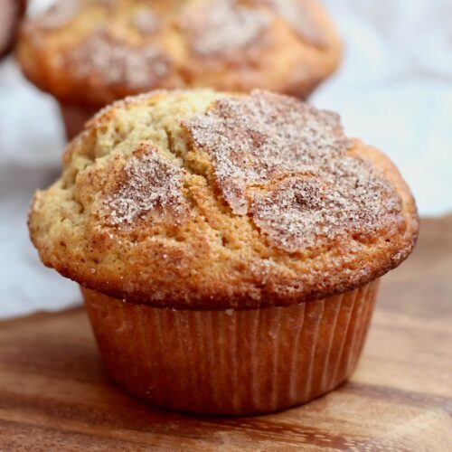 A sourdough cinnamon muffin on a wooden cutting board.