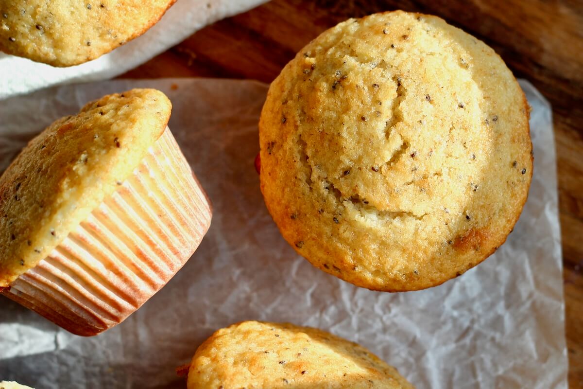 Several sourdough lemon poppyseed muffins on a piece of wrinkled parchment paper.