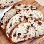 Three slices of chocolate chip sourdough bread on a wooden cutting board.