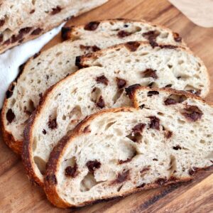 Three slices of chocolate chip sourdough bread on a wooden cutting board.