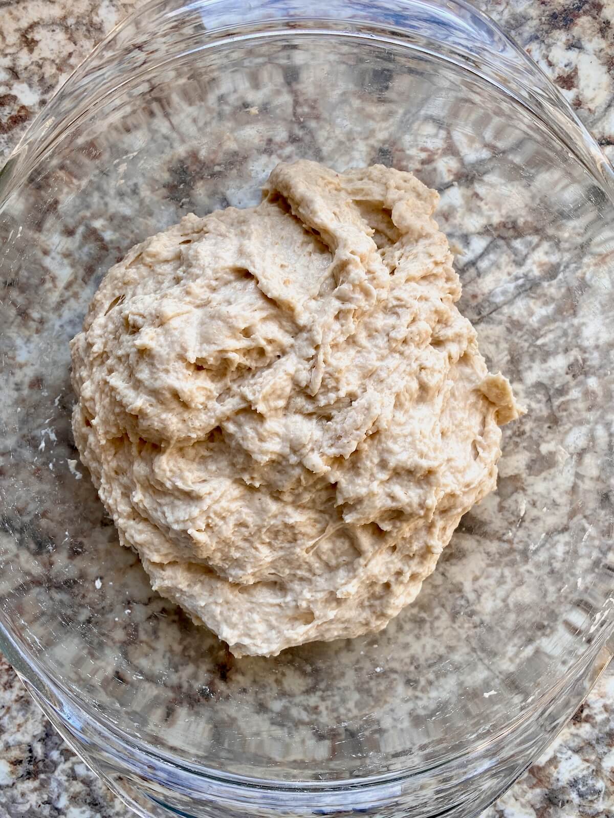 The dough mixed together in a glass mixing bowl.
