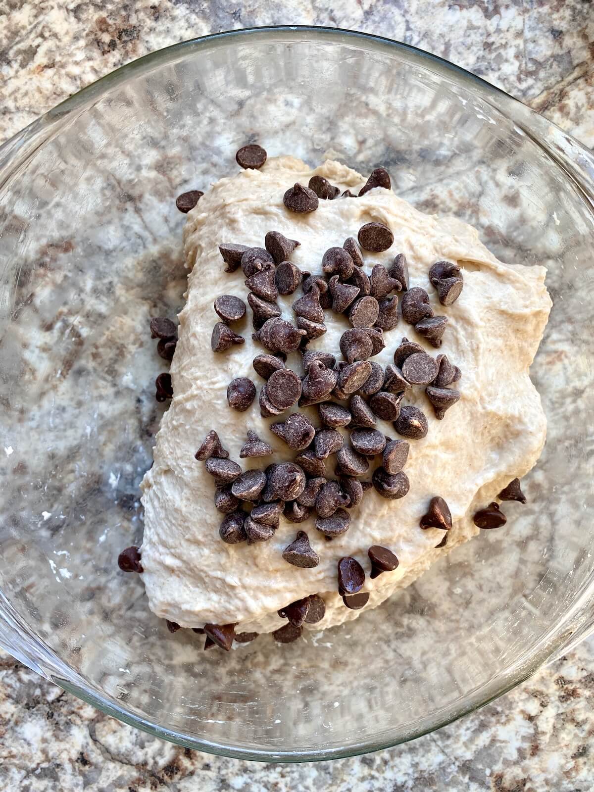 The dough being stretched and folded in a bowl to incorporate the chocolate chips and build gluten.