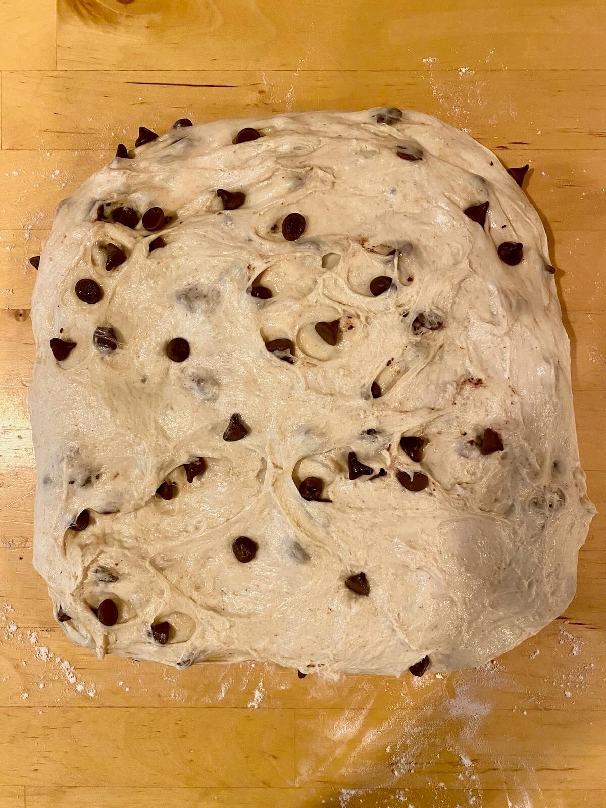 The dough stretched into a large rectangle on a wooden countertop after bulk fermentation.