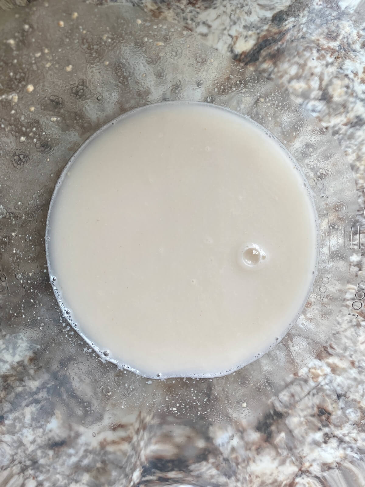Sourdough starter and water mixed together in a glass bowl.