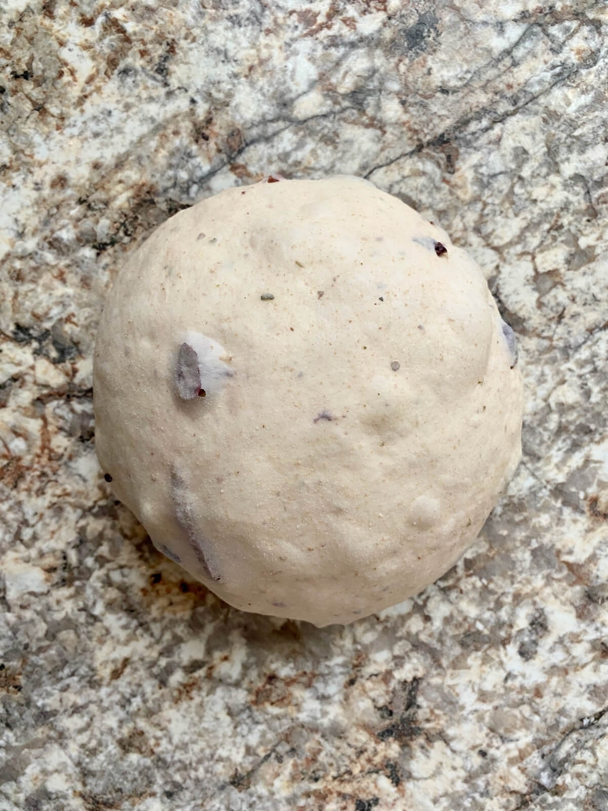 The dough shaped into a boule on a floured countertop.