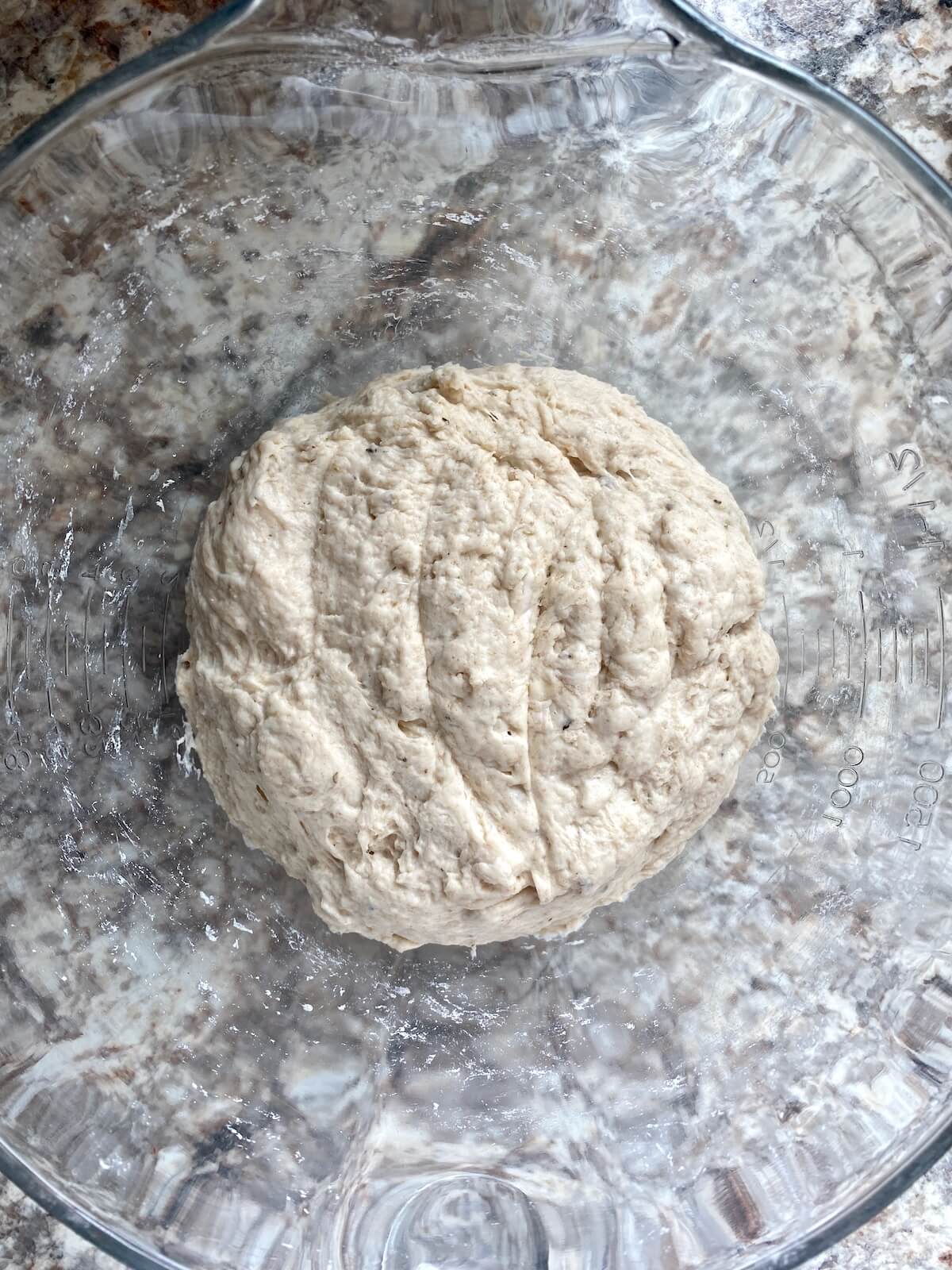 The dough mixed together in a glass bowl before adding olives.