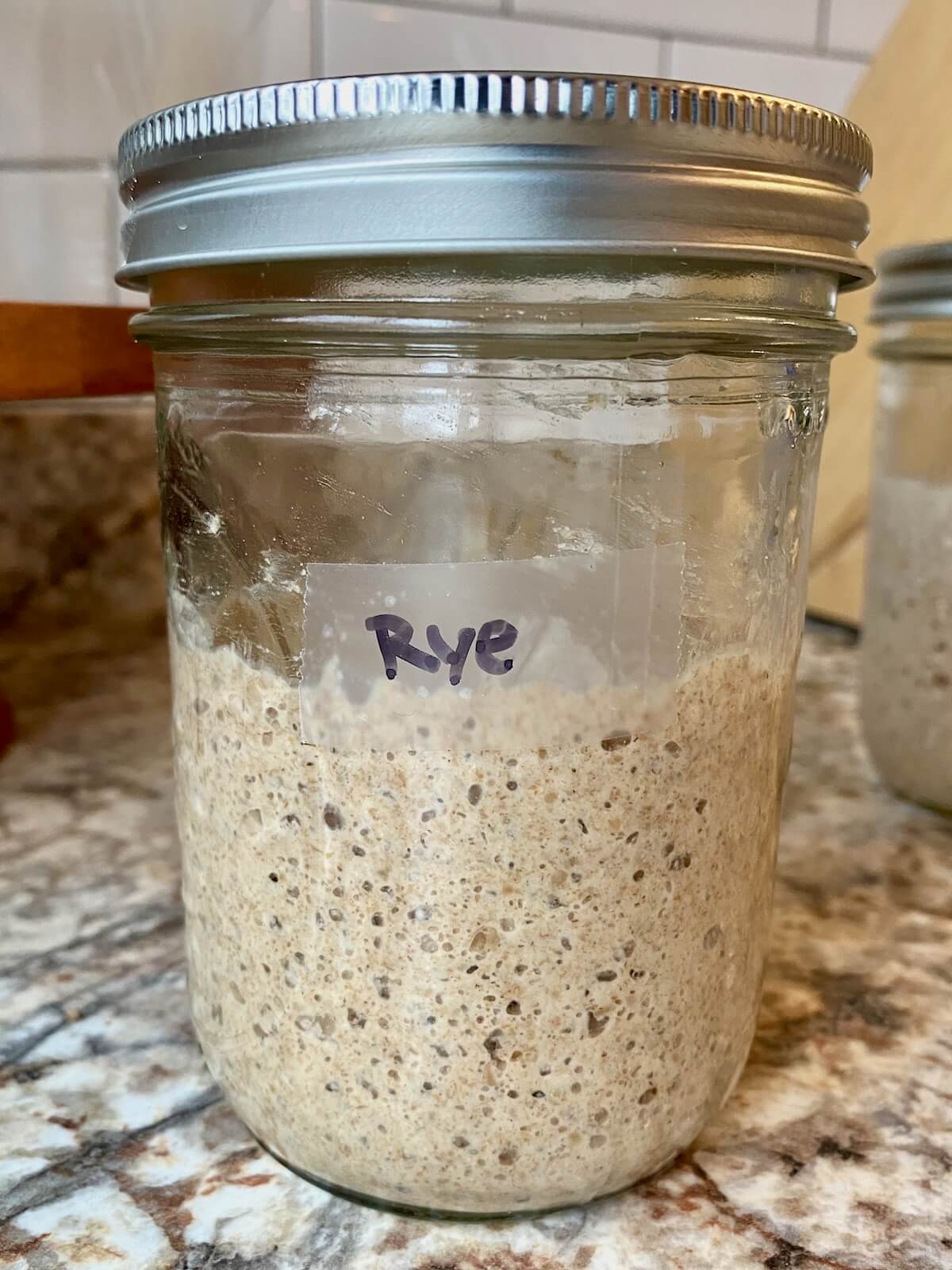An active rye sourdough starter in a glass mason jar.