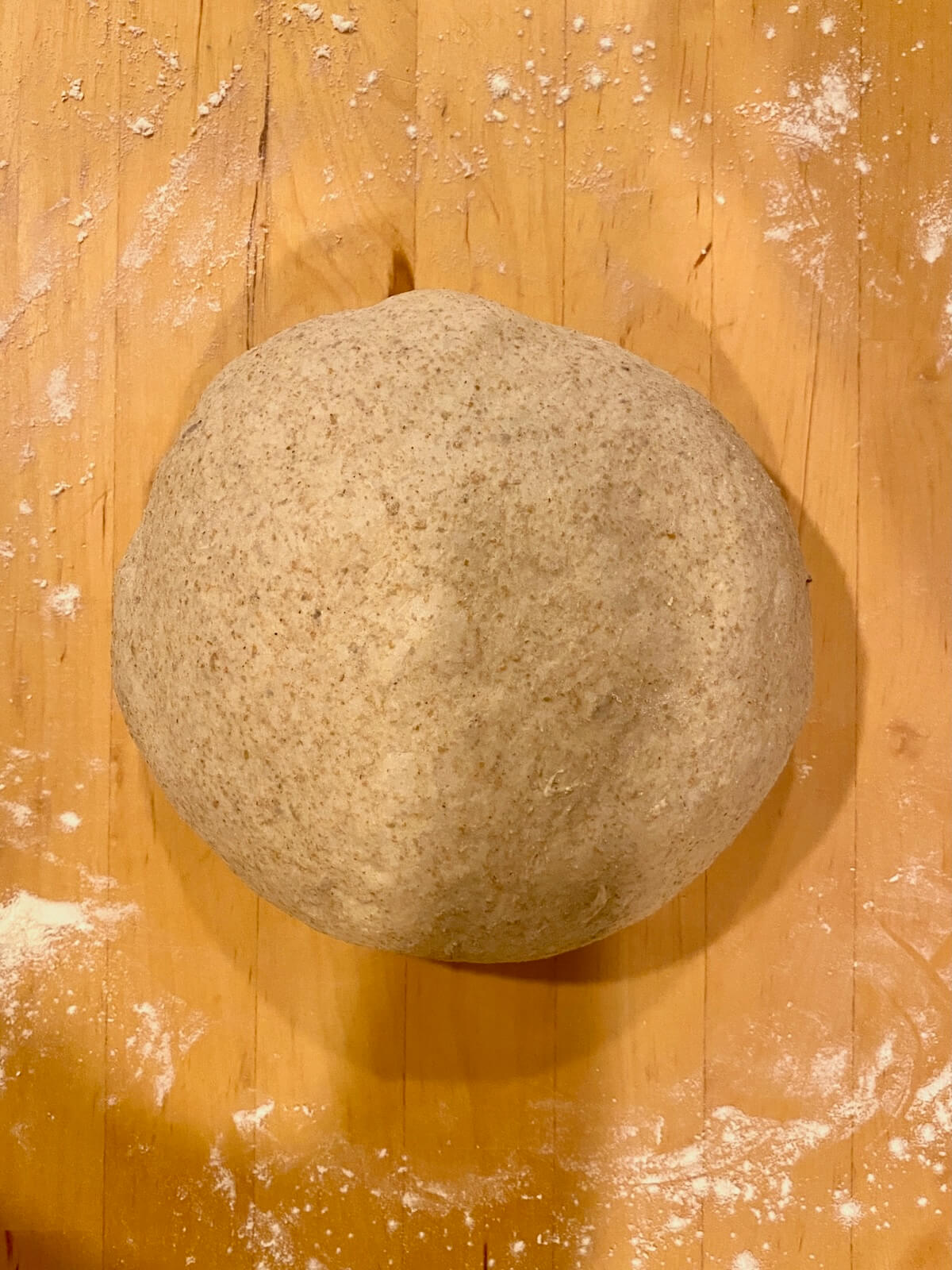 The shaped sourdough rye bread dough on a lightly floured wooden countertop.