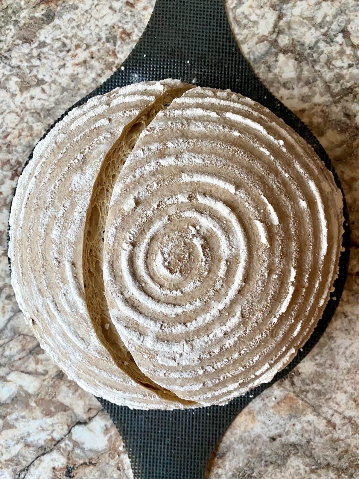 The scored dough on a bread sling ready to be baked.