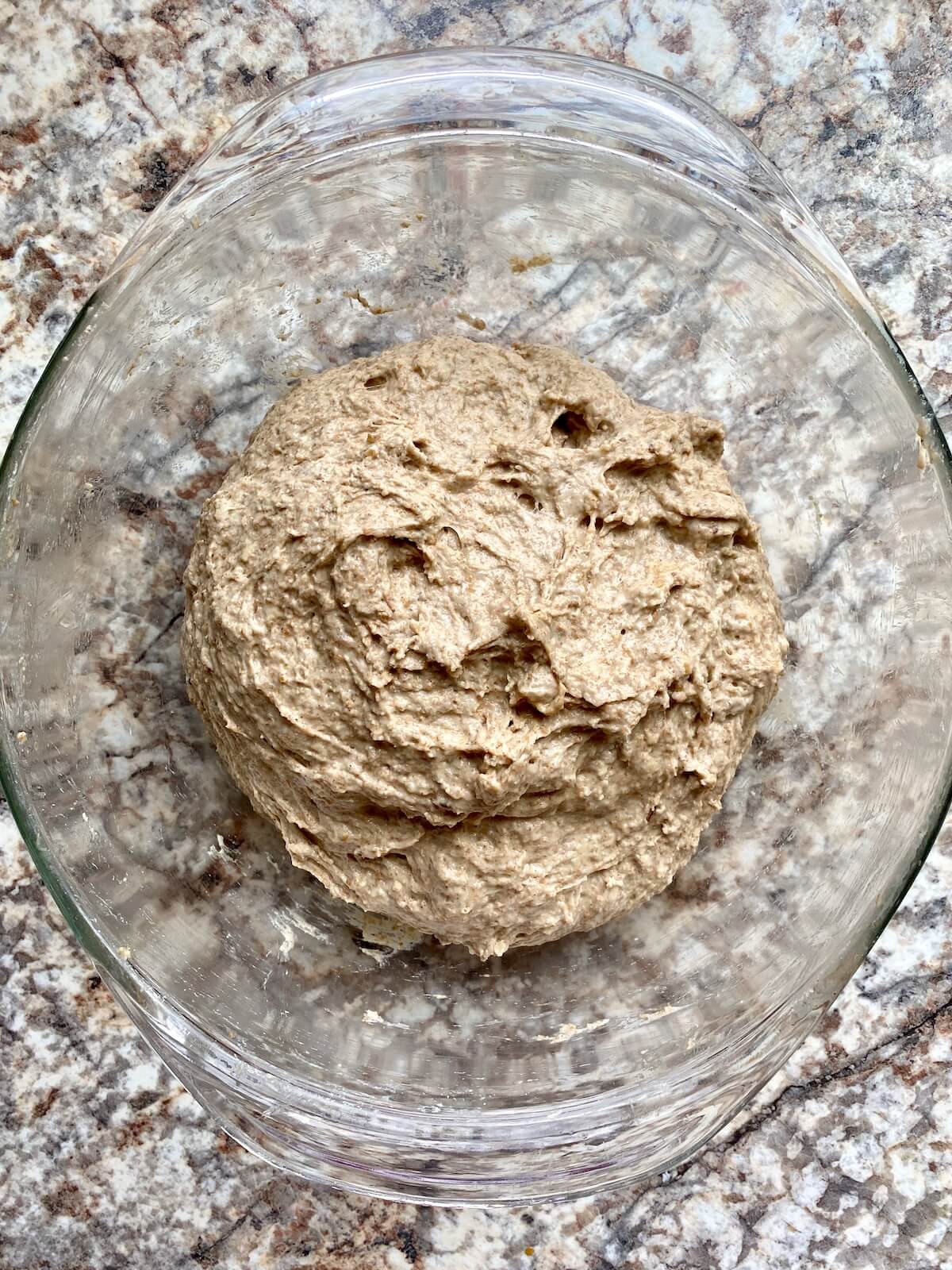 Sourdough rye bread dough in a glass bowl.