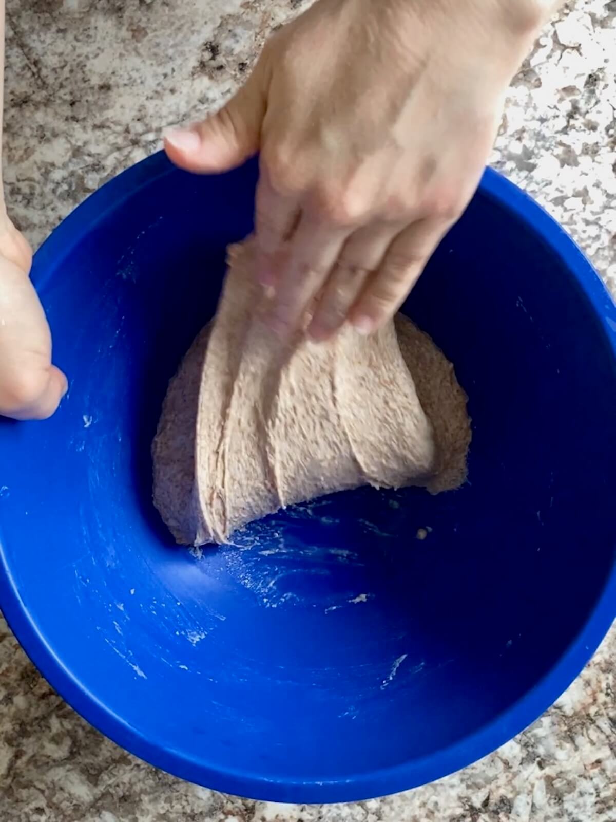 The dough being stretched and folded in a bowl.