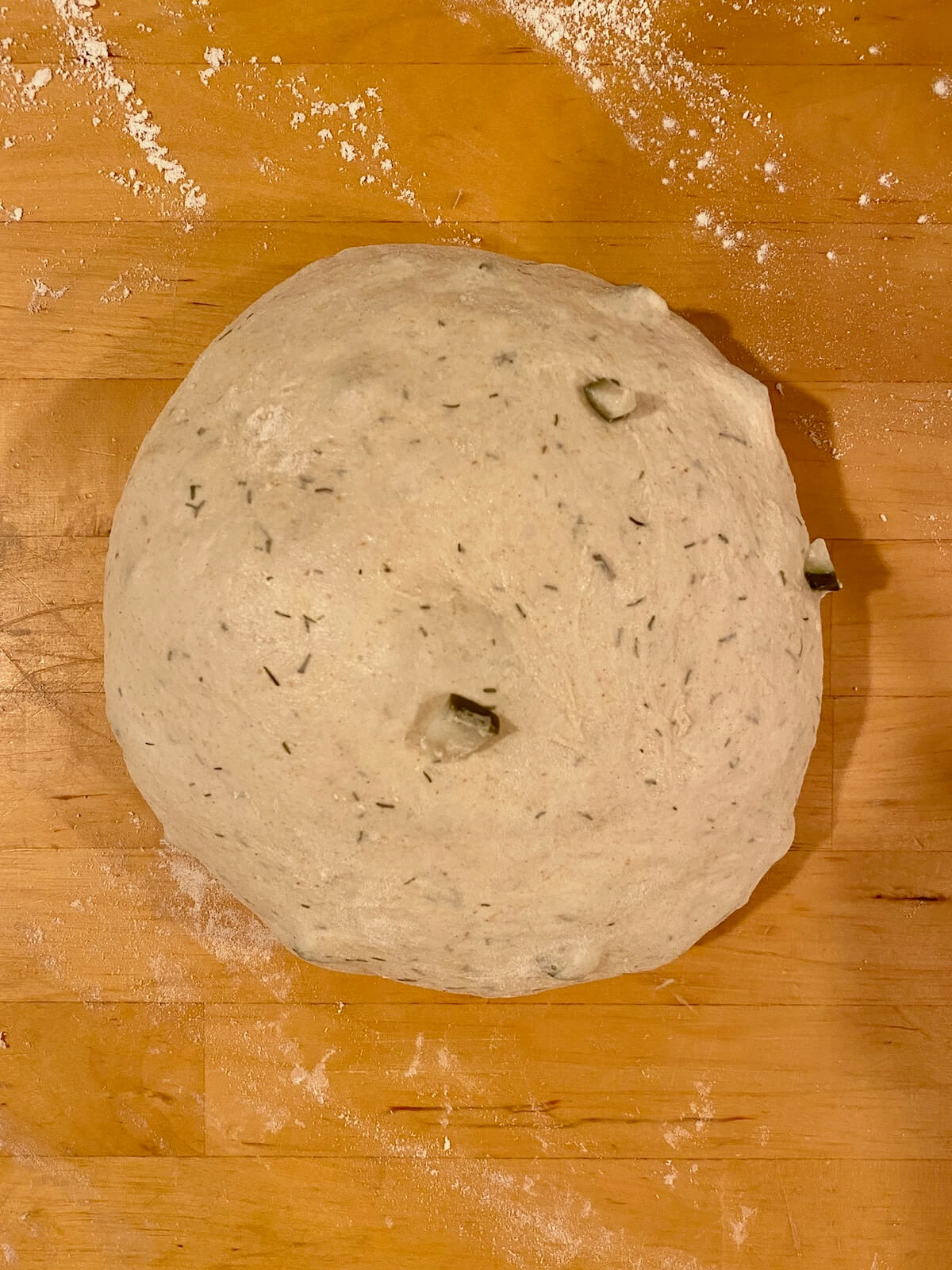 The fermented dough shaped into a ball on a lightly floured counter.