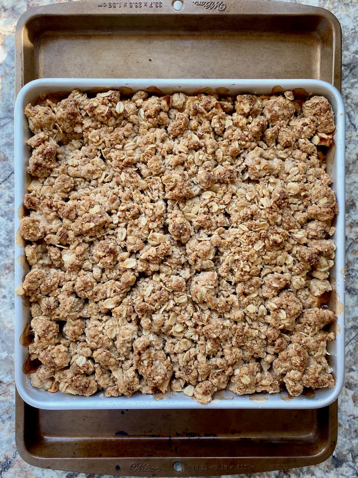 The baked sourdough apple crisp in a square aluminum pan.