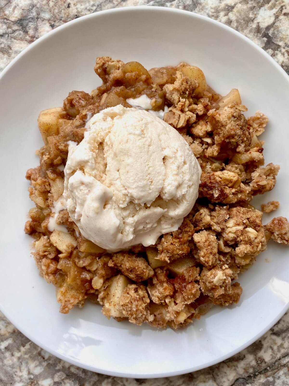 A serving of sourdough apple crisp with ice cream on a small plate.