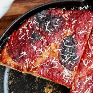 Sourdough pan pizza with pepperoni cut into four pieces in a cast iron skillet.