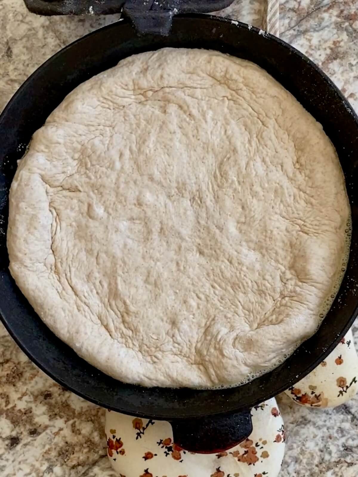 Sourdough pizza dough pressed into a hot, buttered cast iron skillet.