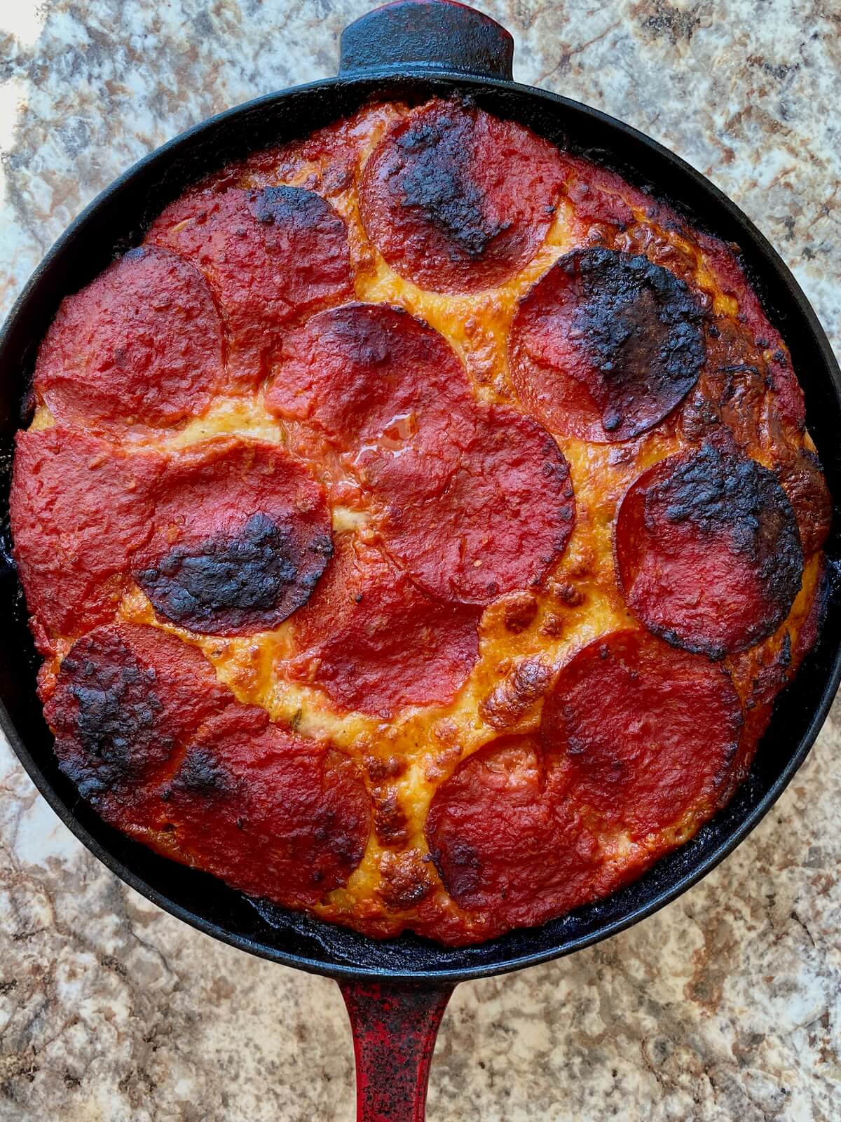The baked sourdough pan pizza with pepperoni in a cast iron skillet.