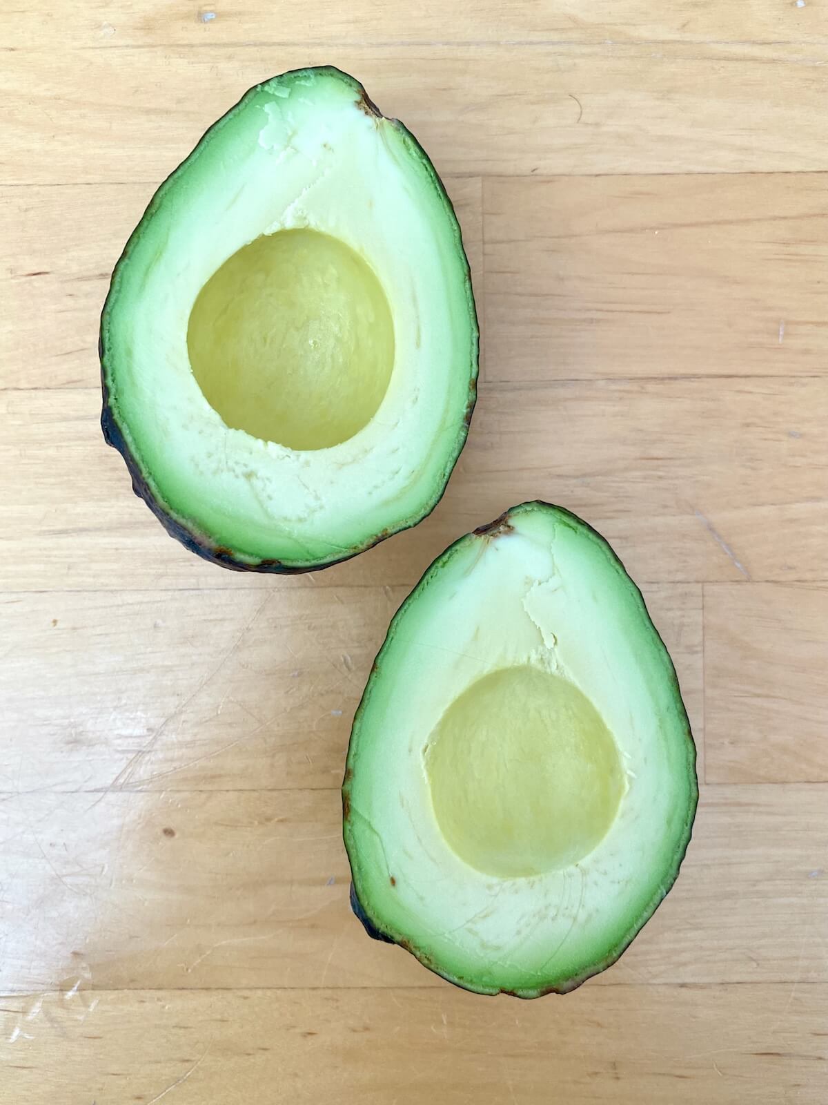 A whole avocado cut in half with the pit removed.