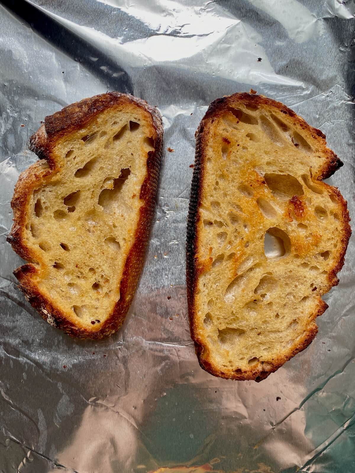Two pieces of toasted sourdough bread on a baking sheet.
