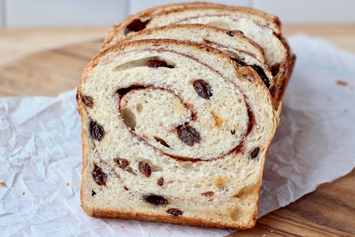 Sliced cinnamon raisin sourdough bread on a cutting board.