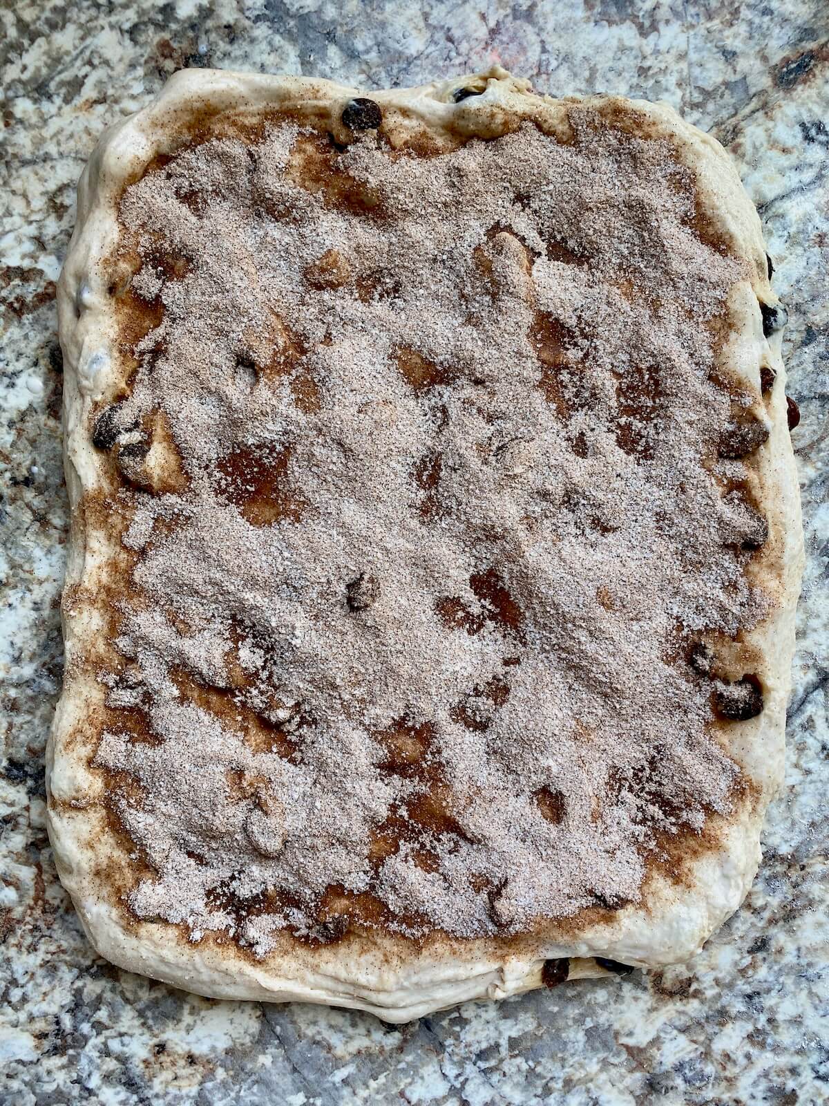 The stretched out dough brushed with milk and topped with the cinnamon sugar mixture.