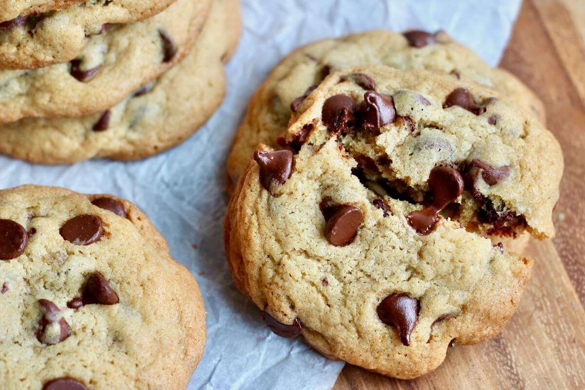 A chocolate chip sourdough cookie split in half with a melty chocolate chip being pulled apart.