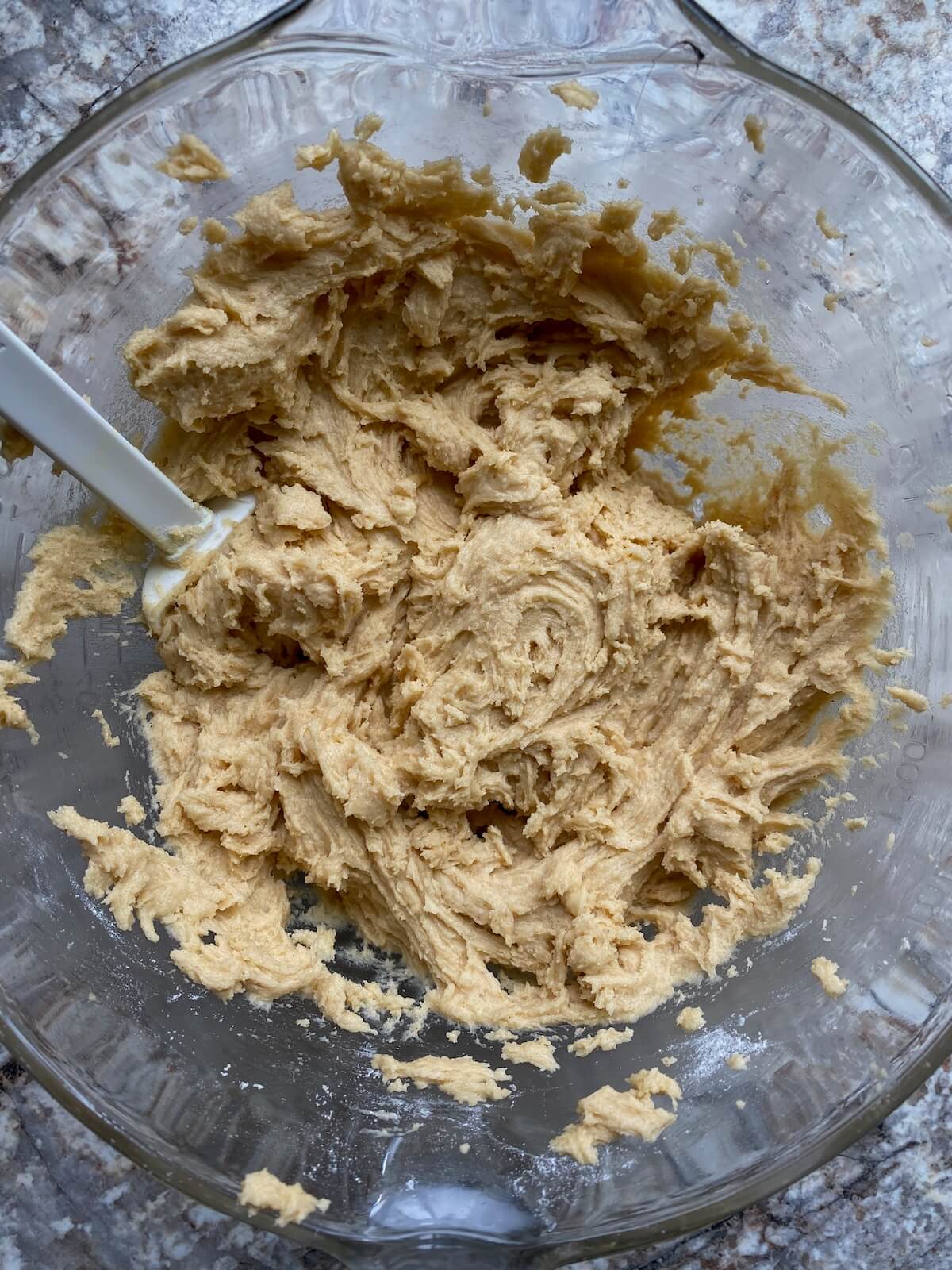 Sourdough discard cookie dough batter in a glass mixing bowl with a rubber spatula.