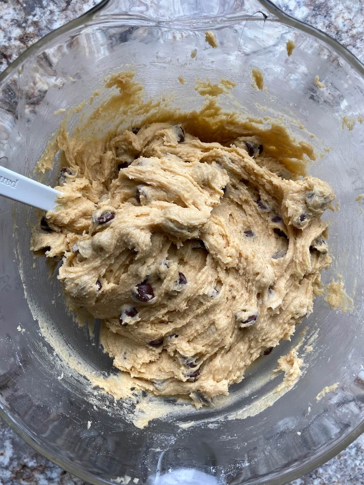 The sourdough chocolate chip cookie dough in a glass mixing bowl.