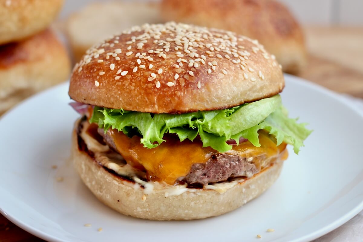 A cheeseburger with lettuce on a sourdough hamburger bun.