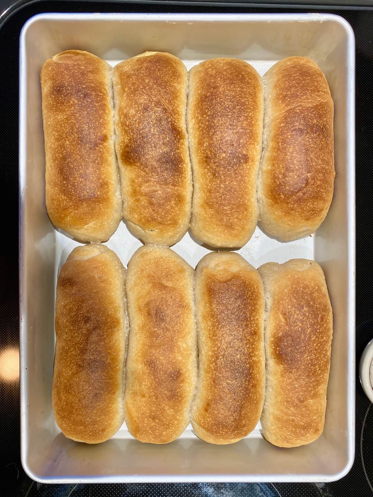 Baked sourdough hot dog buns in a 9x13" pan.