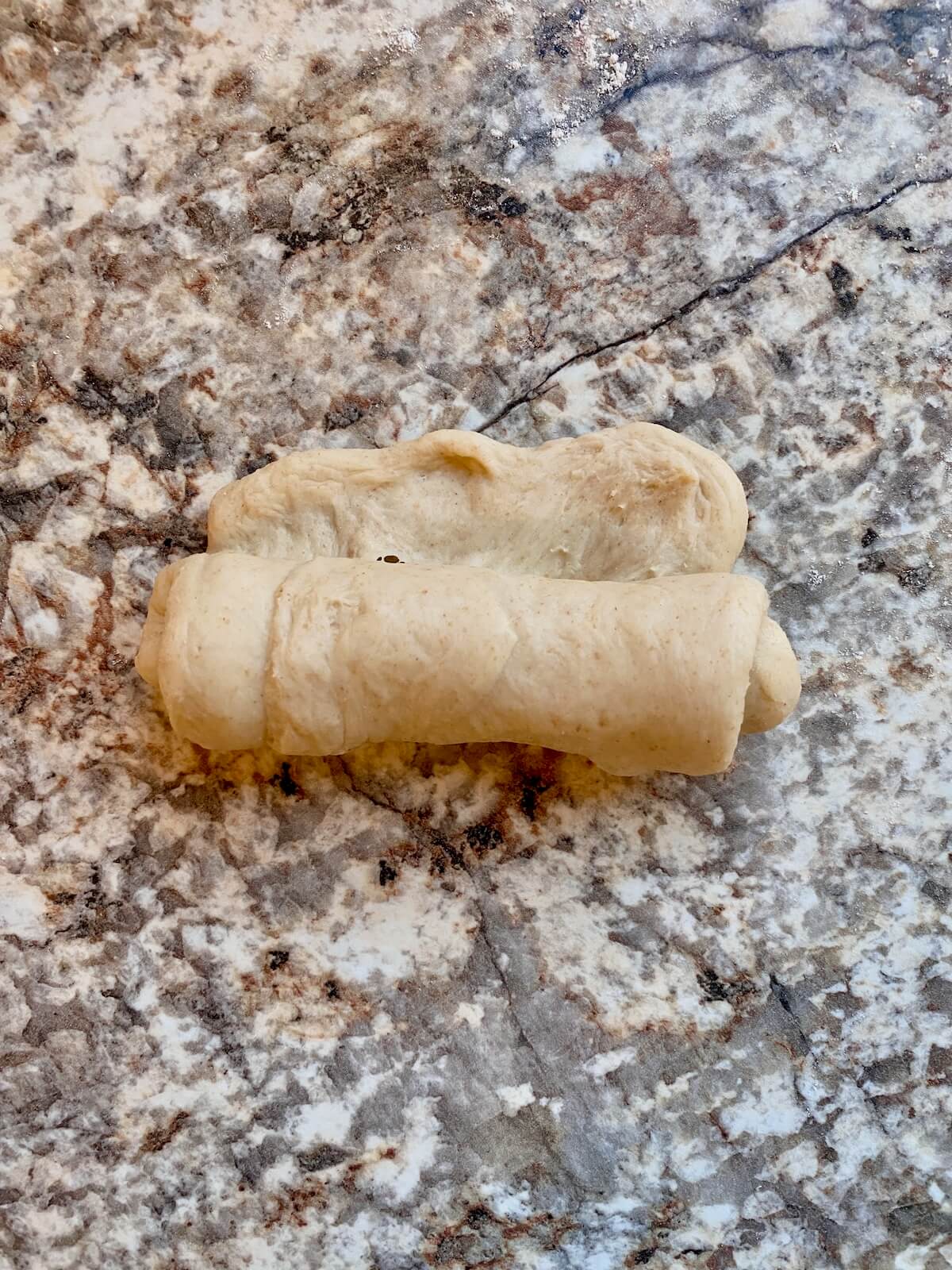 The flattened, rectangular dough being rolled up.