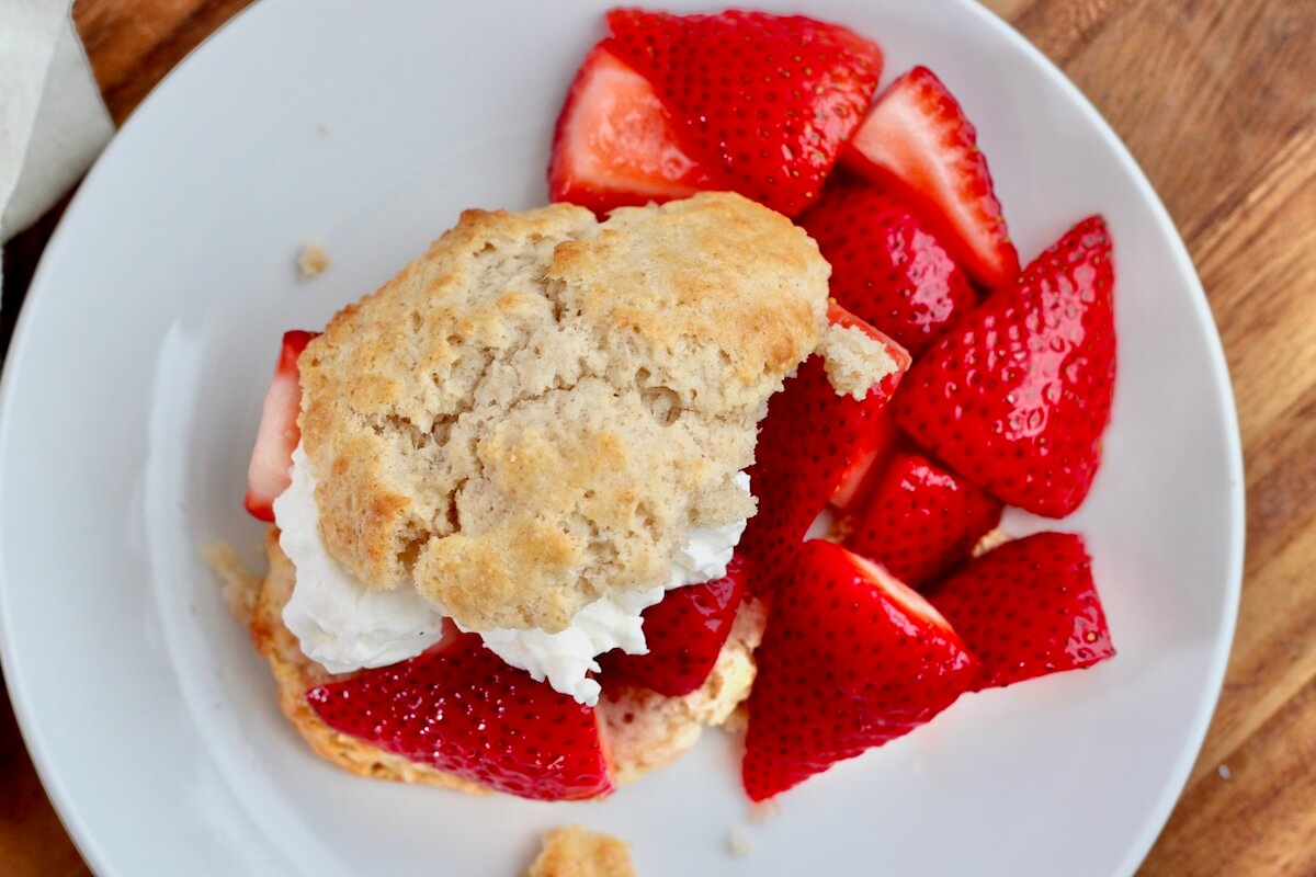 Strawberry shortcake made with a sourdough drop biscuit on a small white plate.