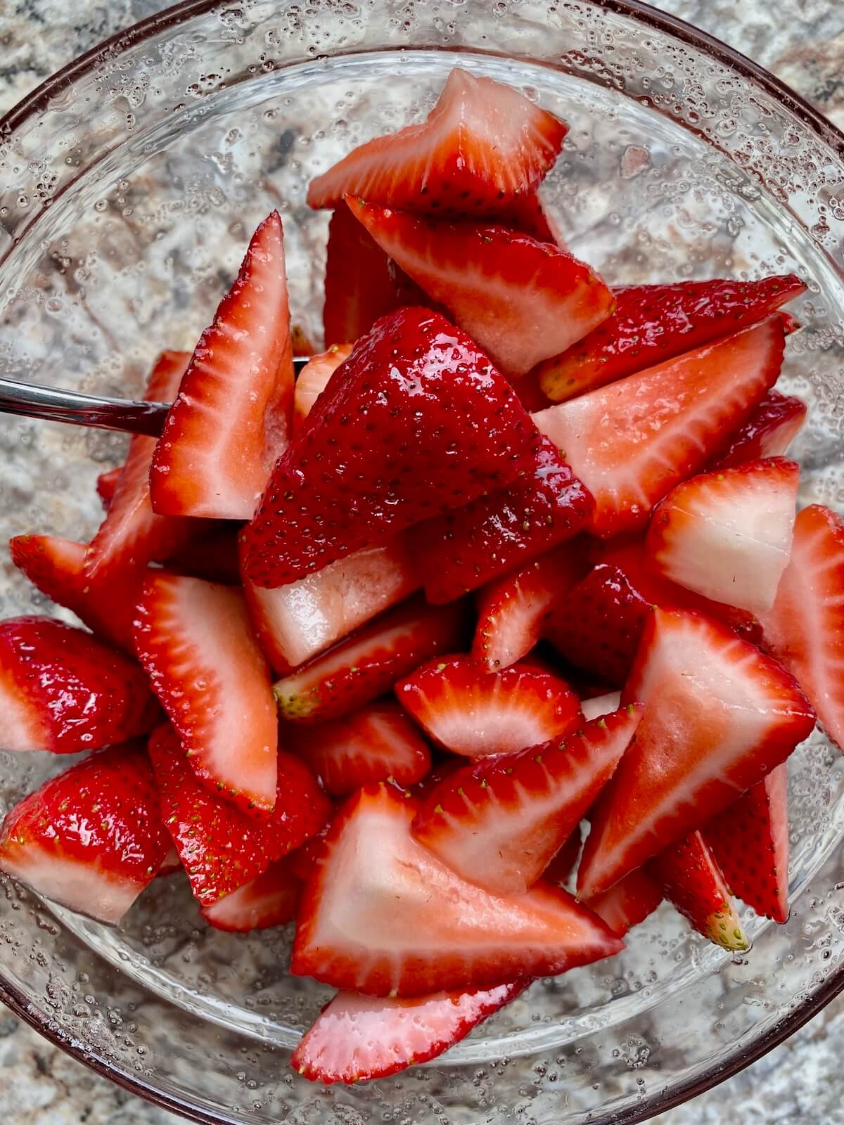 A bowl of quartered strawberries mixed with sugar and lemon juice.