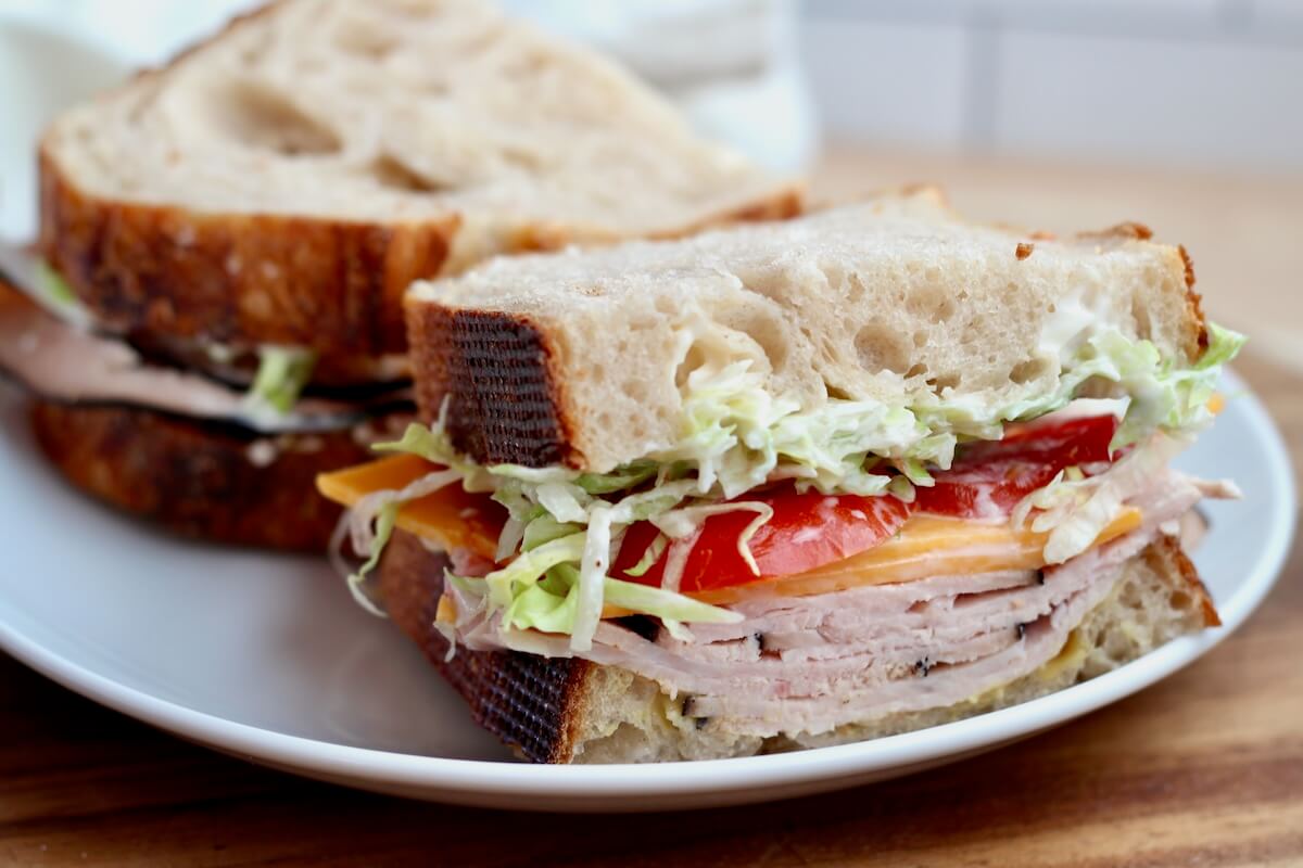 A sourdough turkey sandwich cut in half on a plate.