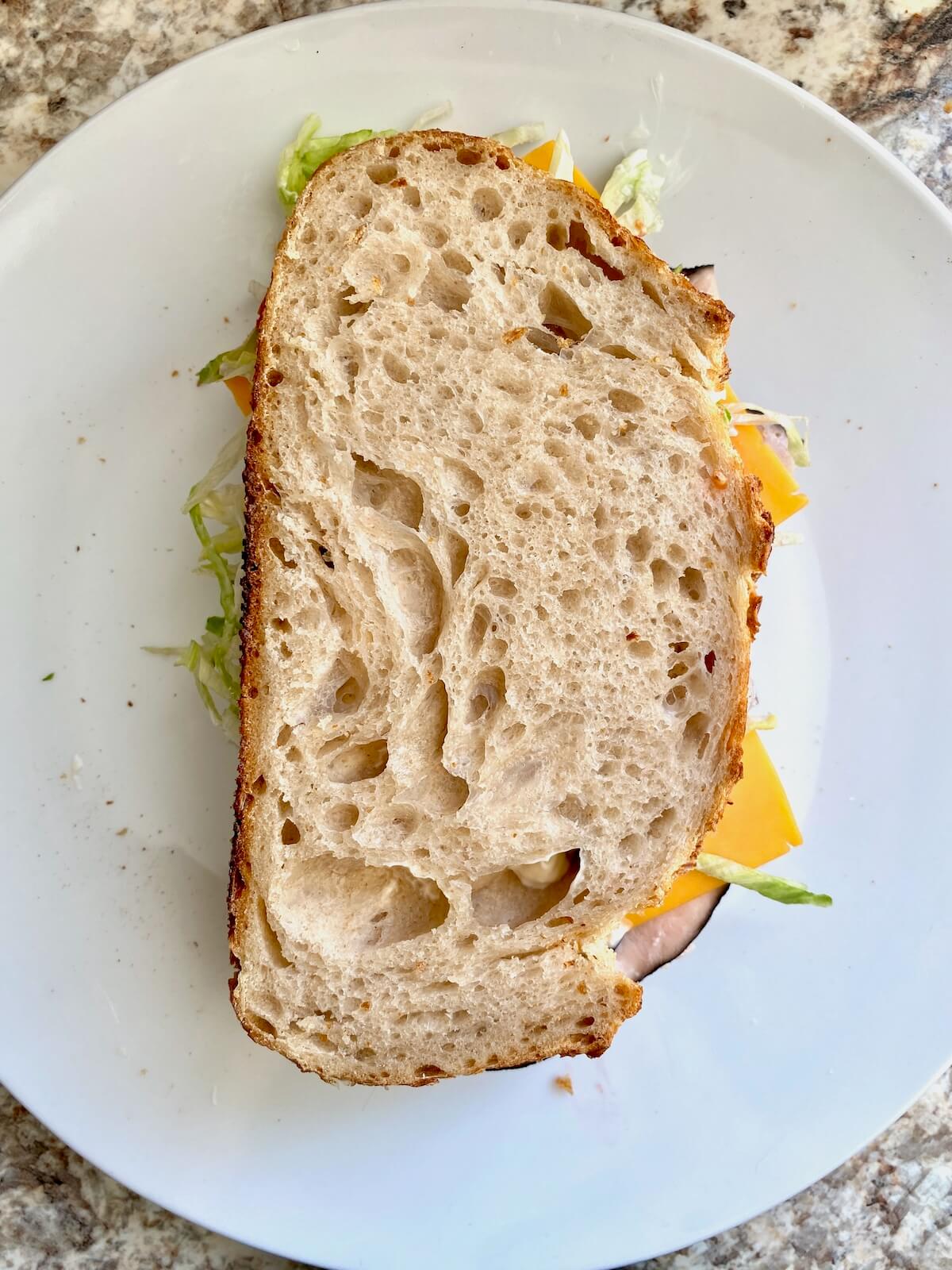 An assembled sourdough turkey sandwich on a small white plate.