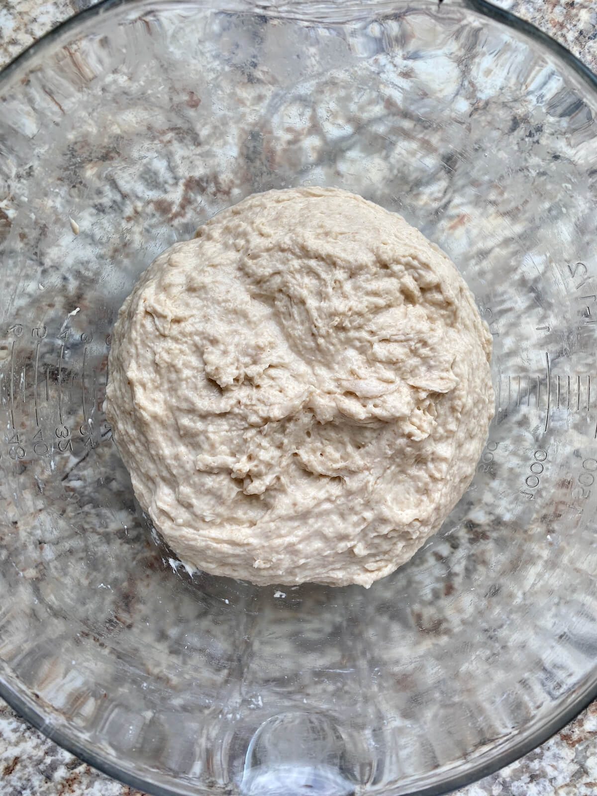 Sourdough bread dough in a glass mixing bowl.