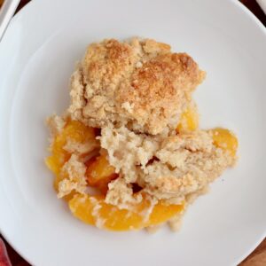 A serving of sourdough peach cobbler on a small plate.