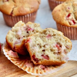 A sourdough strawberry muffin split in half on a paper liner. There are more muffins out of focus in the background.