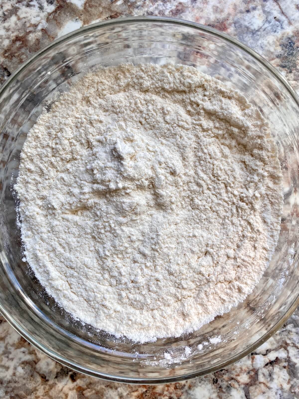 Flour and other dry ingredients mixed in a glass bowl.