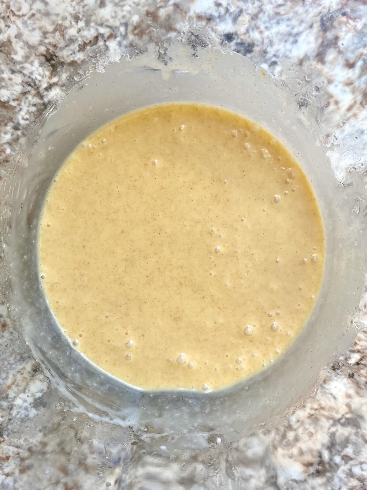 Sourdough discard, cream, eggs, butter, and other wet ingredients mixed together in a glass bowl.