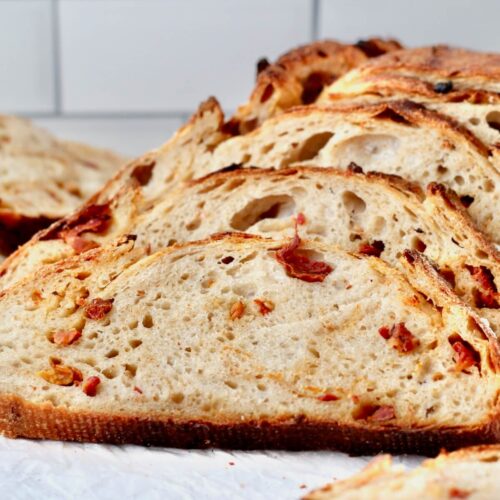 Slices of sun-dried tomato sourdough bread on a cutting board.