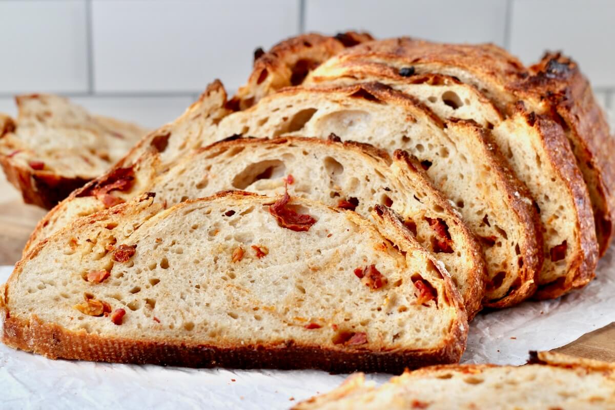 Slices of sun dried tomato sourdough bread on a cutting board.