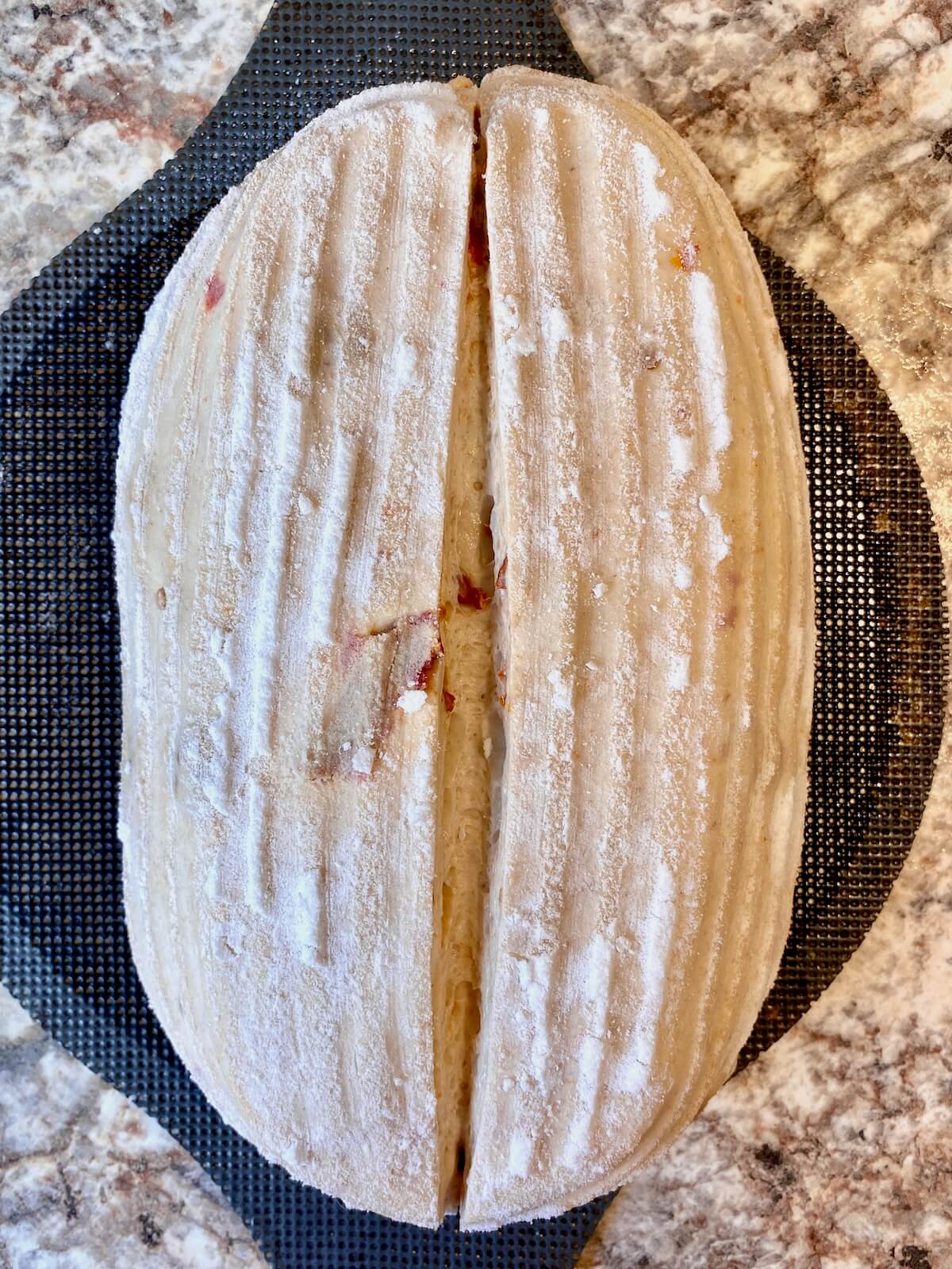 Scored sun dried tomato sourdough bread dough on a bread sling.