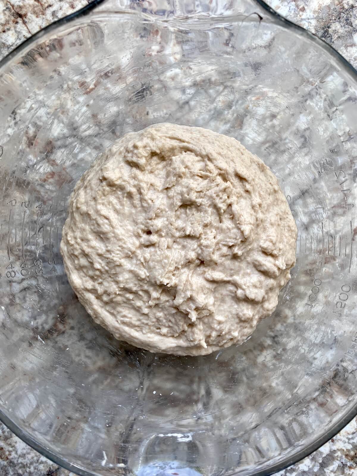 Sourdough bread dough in a glass bowl.