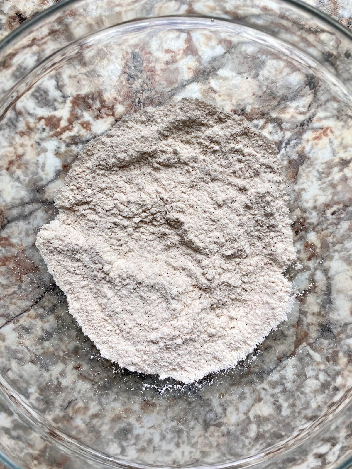 All-purpose flour, cinnamon, and other dry ingredients in a glass bowl.
